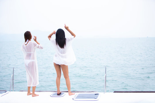 Two Happy beautiful woman in white bikini on  a private yacht deck in the sea