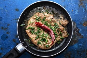 Deep Fried Pork Cooked with Garlic and pepper topped with dried chillies and spring onions on wooden table background