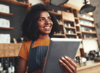 An african female owner of cafe holding digital tablet