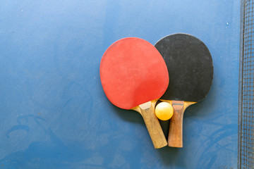 Tabletenis racquet with orange ball isolated on blue background table