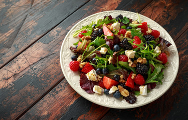 Fresh Fruit Salad with blueberry, strawberry raspberry, walnuts, feta cheese and green vegetables. healthy summer food