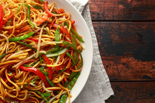 Chow mein, noodles and vegetables dish with wooden chopsticks