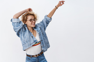 Girl carry away with music vibes dancing carefree smiling broadly waving and raising hands in joy close eyes and relax during awesome party on dance floor turning right wearing denim over white wall