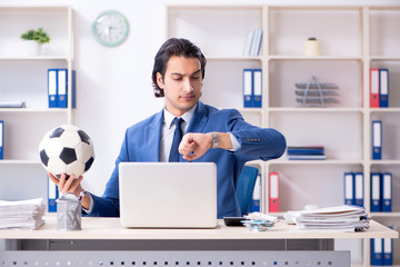 Young handsome businessman with soccer ball in the office 