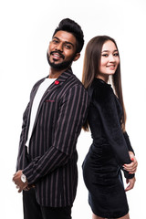 Portrait of a serious young asian couple dressed in formal wear standing back to back over white background