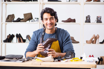 Young man repairing shoes in workshop 