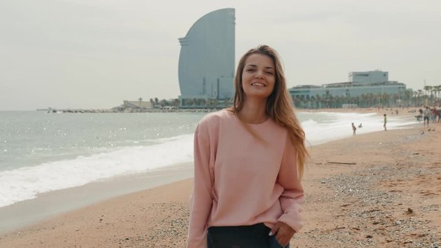 brunette spanish woman walking on beach barcelona spain, tourist happy student girl smiling near sea
