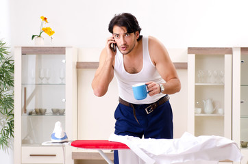 Fototapeta na wymiar Young man ironing in the bedroom