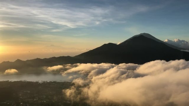 Monkey on background of a volcano in the mountains Bali Indonesia. Monkey goes on the fence on the background of clouds
