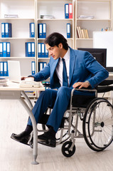 Male employee in wheelchair working at the office 