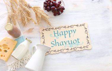 top view photo of dairy products over white wooden background. Symbols of jewish holiday - Shavuot