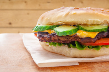 fresh flavored cheeseburger with juicy cutlet, cucumbers, tomato and lettuce