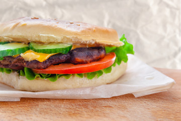 fresh flavored cheeseburger with juicy cutlet, cucumbers, tomato and lettuce