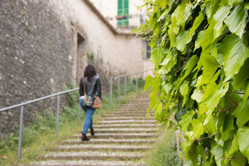 Fototapeta na wymiar A girl walks up stairs in an Italian town.