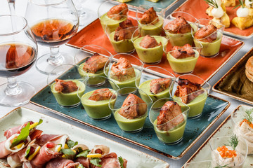Grilled meat fillet with green mousse in glass cups on banquet table. Catering food, canape and snacks.