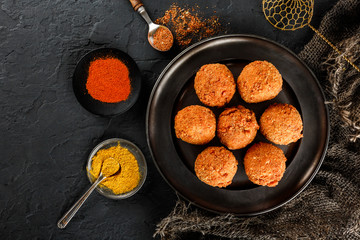 Fried potato cheese balls or croquettes with spices on black plate over dark stone background. Unhealthy food, top view