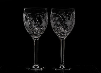 Two crystal wine glasses with a drink, falling ice and splashes