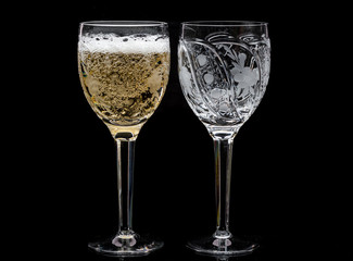 Two crystal wine glasses with a drink, falling ice and splashes