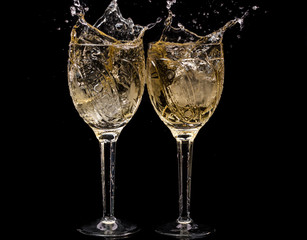Two crystal wine glasses with a drink, falling ice and splashes