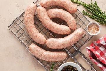 Raw sausages on grill grate with herbs and spices.