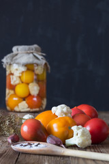 Preparation of fermented vegetables. Fresh tomatoes,cauliflower,spices in the foreground. Dark background. Copy space
