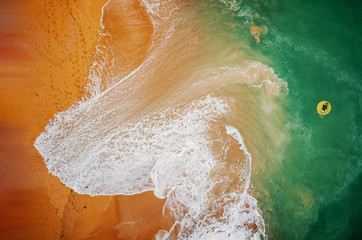 Fototapeta premium Aerial view of woman swimming on the yellow swim ring in the turquoise sea.. Top view from drone