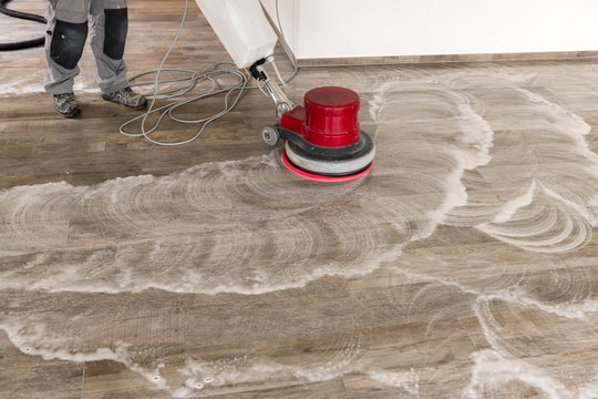 Floor cleaning with a machine. A man is cleaning a tiled floor in an apartment.