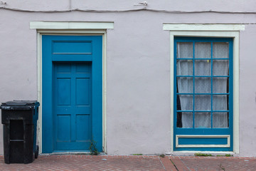 Fototapeta na wymiar Blue door and window on side of home in urban area