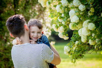 Young father and his smiling son in the park, hugging and enjoying time together, father's day celebration