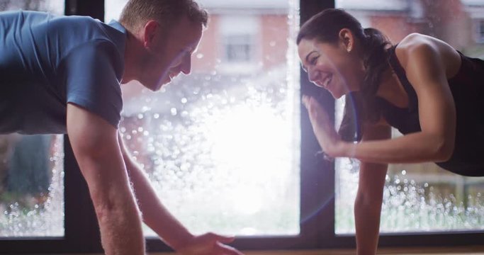 4K Happy couple getting fit together, smiling & laughing during workout. Slow motion.