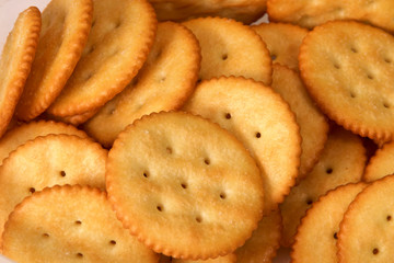Close up of golden brown butter crackers showing salt, holes, and ridges.