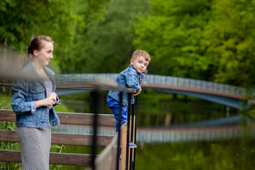 Mother is experiencing that the child will fall into the water. A little boy climbs a bridge railing in the park. The threat of drowning. Danger to children