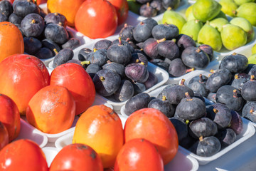 A background of fresh figs and persimmon for sale at a market