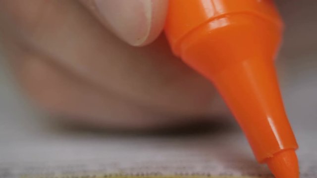 Close up of student hand underlining a document on a desk at home. Highlighter  in man hand  marked text in book, education concept. Closeup. Thumbing pages and highlighting text with marker. UHD 4K.