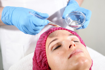 Naklejka premium A cosmetologist puts a remedy on the face for the patient to nourish, moisturize and rejuvenate the skin. Cosmetology procedure in cosmetology clinic.