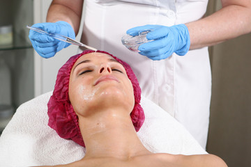 The face of the patient close-up at the beautician's appointment. Applying a means of rejuvenation on the face. Photos in the interior.Doctor's hands are out of focus.