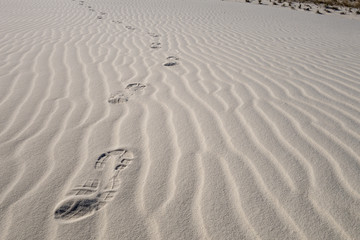 Footsteps in the white desert sand of the Desert Sands National Monument in New Mexico, USA. Symbol for loneliness, solitude, desolation, adventure, determination