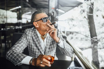 Beautiful day,businessman in suit with suspicious face drinks romm beverage and smokes