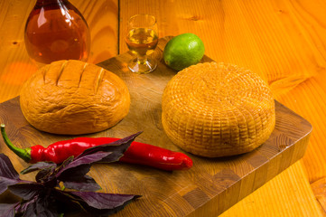 national Adyghe cheese homemade on a cutting Board with a knife, Basil, parsley, lime, sesame oil,...