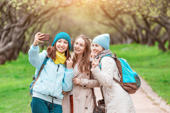 Three young pretty girls making selfie photo in spring park, sisterhood concept