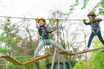 Two cute happy young children, boy and girl in protective harness, carbine and safety helmets on...