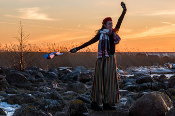Girl at the beach with Estonian national clothes and flag.