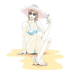 beautiful elegant girl in bikini, hat and sunglasses sits on sand beach and drinks cocktail