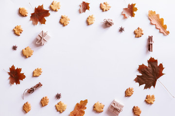 Fototapeta na wymiar Hello Autumn flat lay background. Top view of wreath with maple leaves and yellow flowers, honey biscuits and cookies.