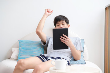 Young man is gesture happiness while holding a tablet.