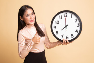 Young Asian woman thumbs up with a clock.