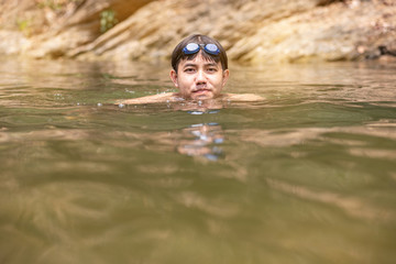 Asian man with goggles on head swimming in river, Handsome man enjoy swimming in water 