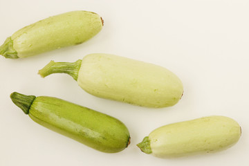 Courgettes arranged on a white background in random order, top view