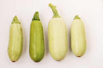 Courgettes arranged on a white background in random order, top view