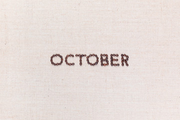 The word October written with coffee beans shot from above, aligned in the center.